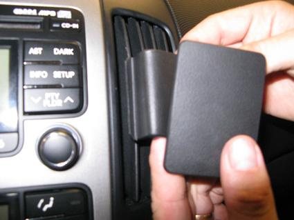 En hand håller en svart detalj som passar i bilens instrumentbräda.