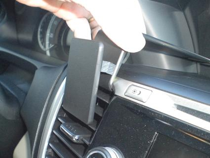 En hand fäster en svart hållare på bilens instrumentpanel.