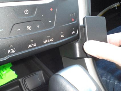 En hand trycker på en kontrollpanel i en bil.