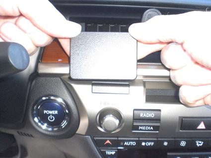 Händer fäster en svart monteringsbygel på instrumentbrädan i en bil.