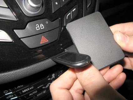 En hand som öppnar ett fack i bilen, vid kontroller och knappar.