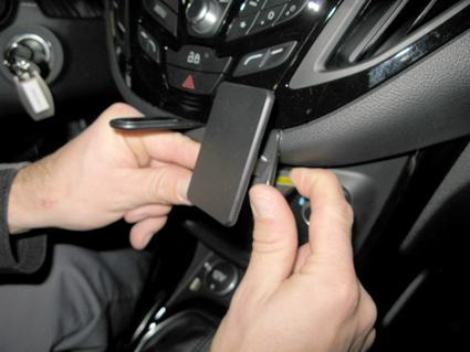 En person monterar en enhet på bilens instrumentbräda.