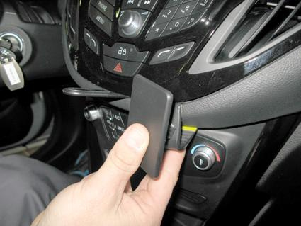 En hand håller en vinklad enhet på bilens instrumentbräda.