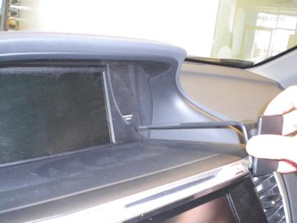 En hand håller i ett verktyg vid bilens instrumentpanel.