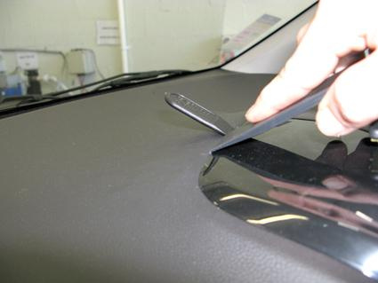 En hand som justerar en monteringsbygel på instrumentbrädan i en bil.