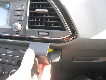 En hand som kopplar in en enhet i en bils instrumentbräda.