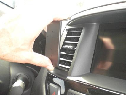 En hand håller i en del av instrumentpanelen i en Nissan Pathfinder.