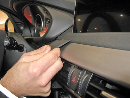 En hand placerar en monteringsbygel på instrumentpanelen i en bil.