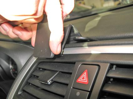 En hand tar bort en del från bilens instrumentbräda.