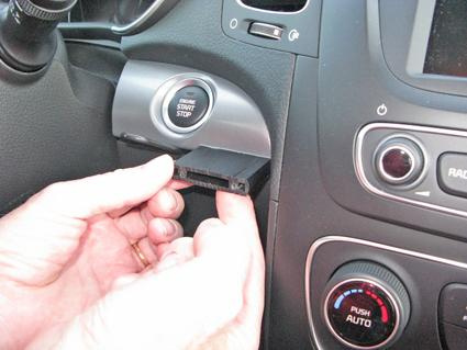 En hand kopplar in en modul i en bils instrumentpanel.