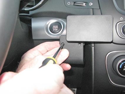 En hand håller en skruvmejsel vid en komponent i en Kia Sorento.