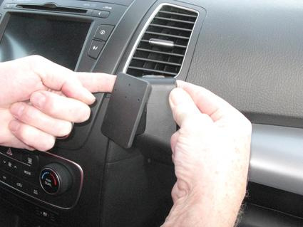 Person som installerar en del i en bilinteriör, troligtvis en Kia Sorento.