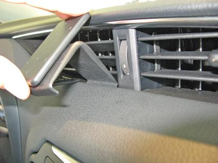 En hand placerar en del i en ventilationsrist i en Toyota Yaris.