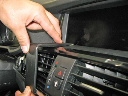 En hand som installerar en monteringsbygel i BMW X3:s interiör.