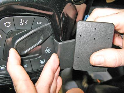En hand som fäster en del vid bilens kontroller.