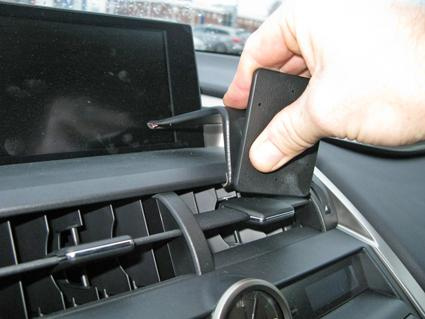 En hand fäster en vinklad monteringsbygel i en bils instrumentpanel.