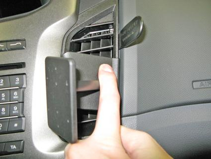 En hand som installerar en vinklad hållare i en bilventil.