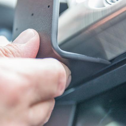 En hand fäster en monteringsbygel i en bilinteriör.