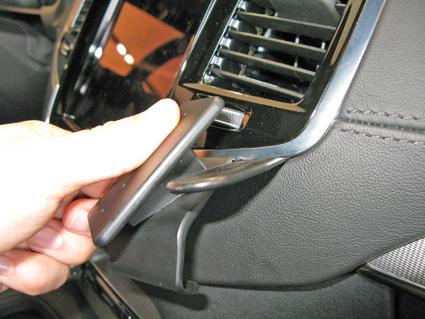 En hand placerar en enhet på en ventilationsgrill i en Volvo XC90.