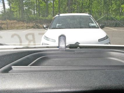 Bilden visar en bil i en parkeringsplats med träd i bakgrunden.