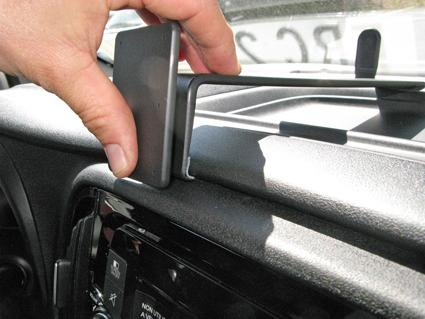 En hand placerar en enhet på instrumentbrädan i en Fiat Doblo.