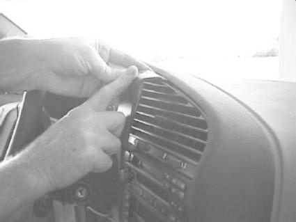 Händer som installerar en monteringsbygel på en bils instrumentpanel.