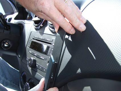 En hand installerar en monteringsbygel på en bils instrumentpanel.