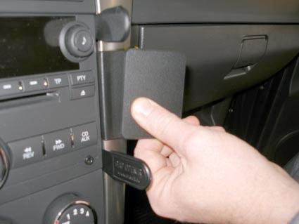 En hand som fäster en monteringsbygel på bilens instrumentpanel.