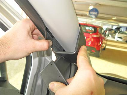 En hand som installerar en monteringsbygel i en bilinteriör.
