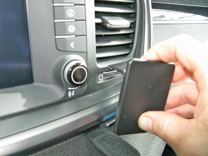 En hand placerar en monteringsbygel i en bils armaturpanel.