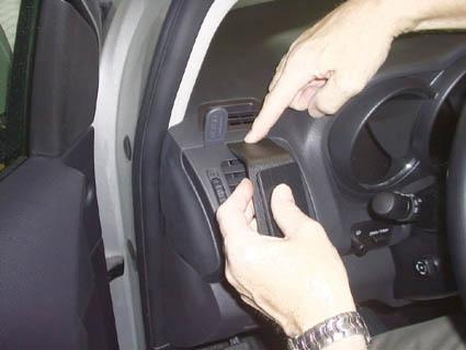 Ett hand som pekar på en monteringsbygel i en bil.