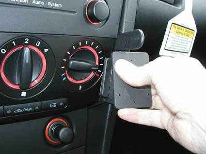 En hand installerar en monteringsbygel i instrumentpanelen på en Mazda 3.