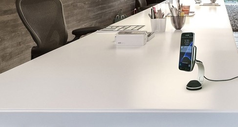 En smartphone på en laddare på ett modernt kontorsbord.