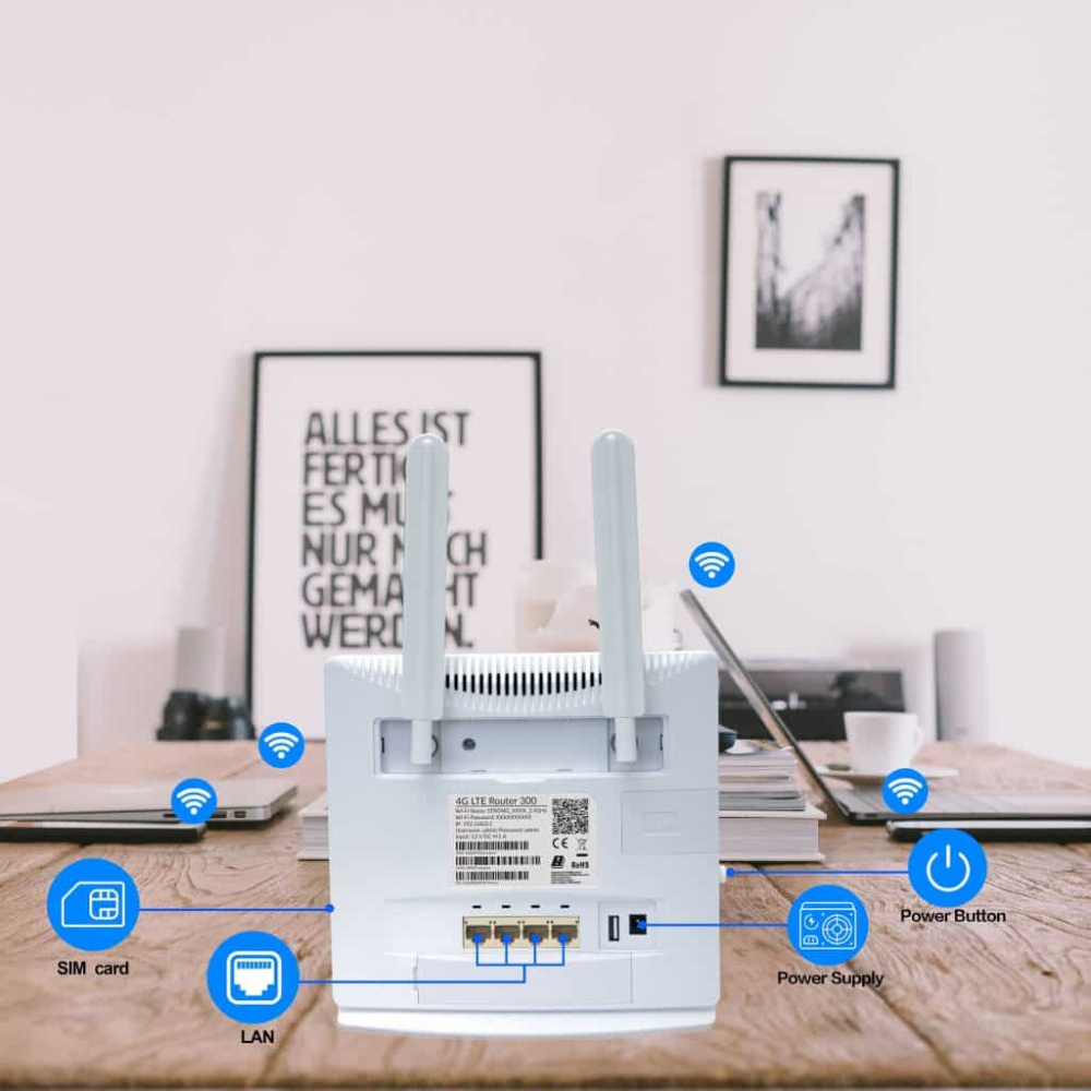 Router med antenner, portar och anslutningar på ett skrivbord med laptopar i bakgrunden.