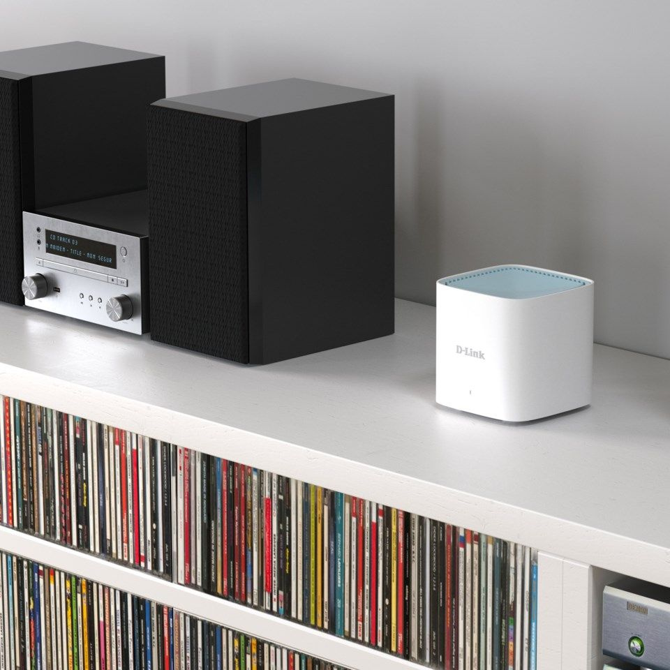 Ett D-Link mesh-system i vitt, placerat på en hylla med ljudutrustning och cd-skivor.