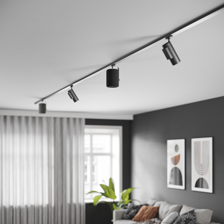 En modern inredning med taklampor, gardiner, växt och konstverk på väggen.