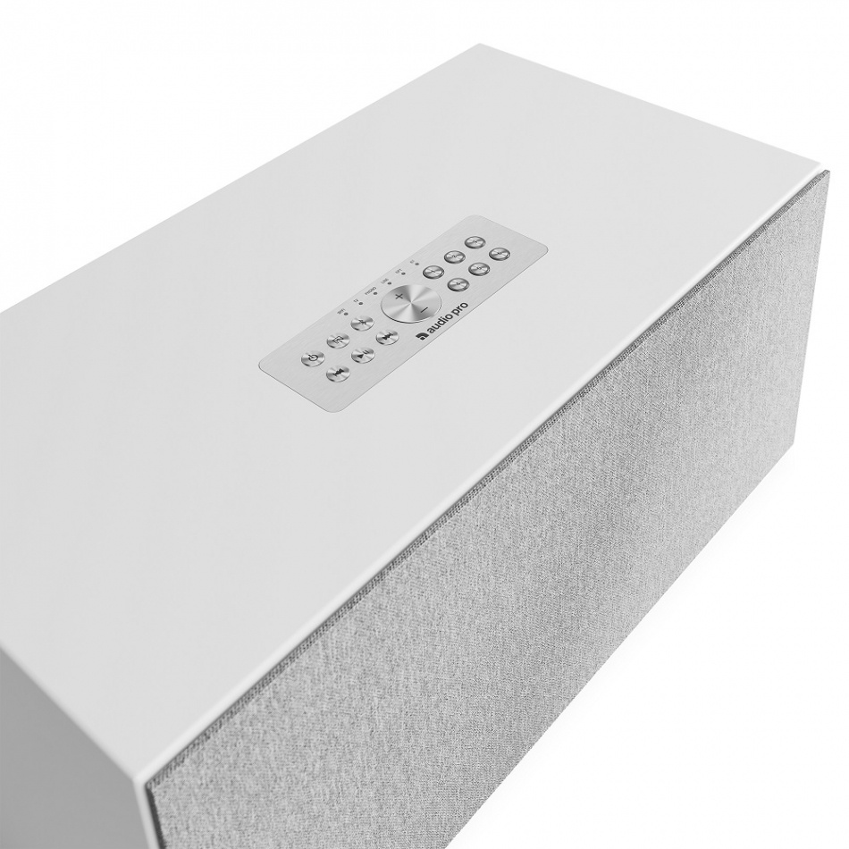 Högtalare med vit design, kontroller på toppen och tygfront.