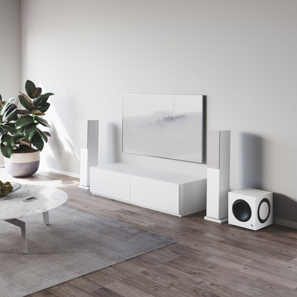 En modern inredning med vit aktiv subwoofer och ljudsystem i ett ljust rum.