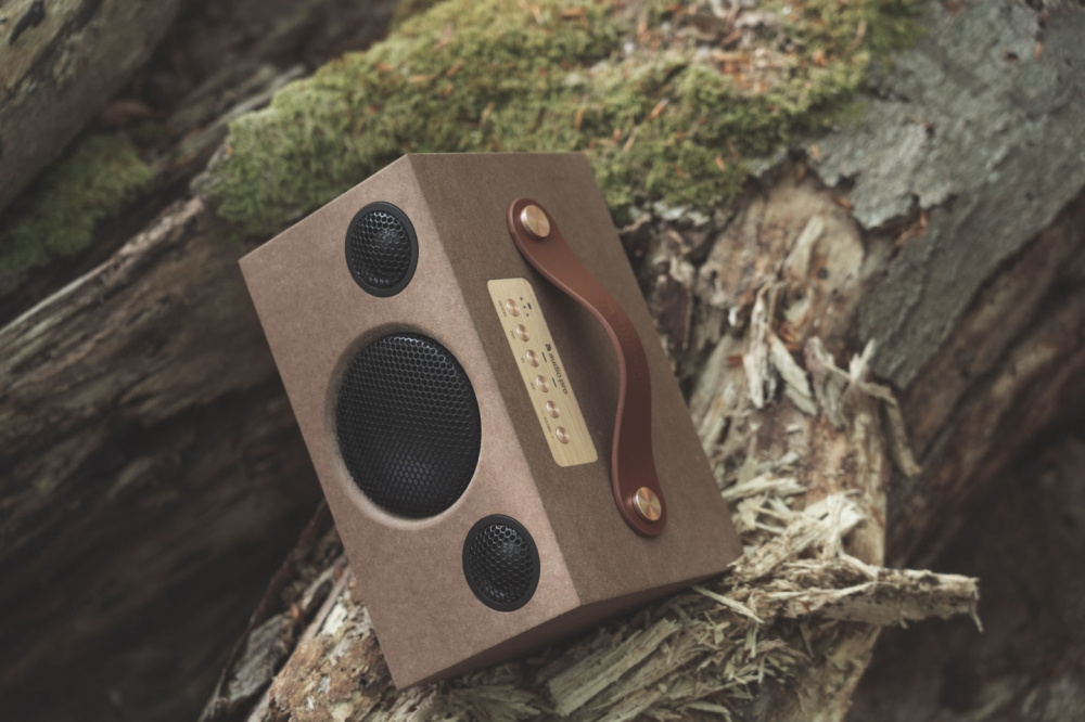 Bluetooth-högtalare i kompakt design med läderhandtag och trämaterial.