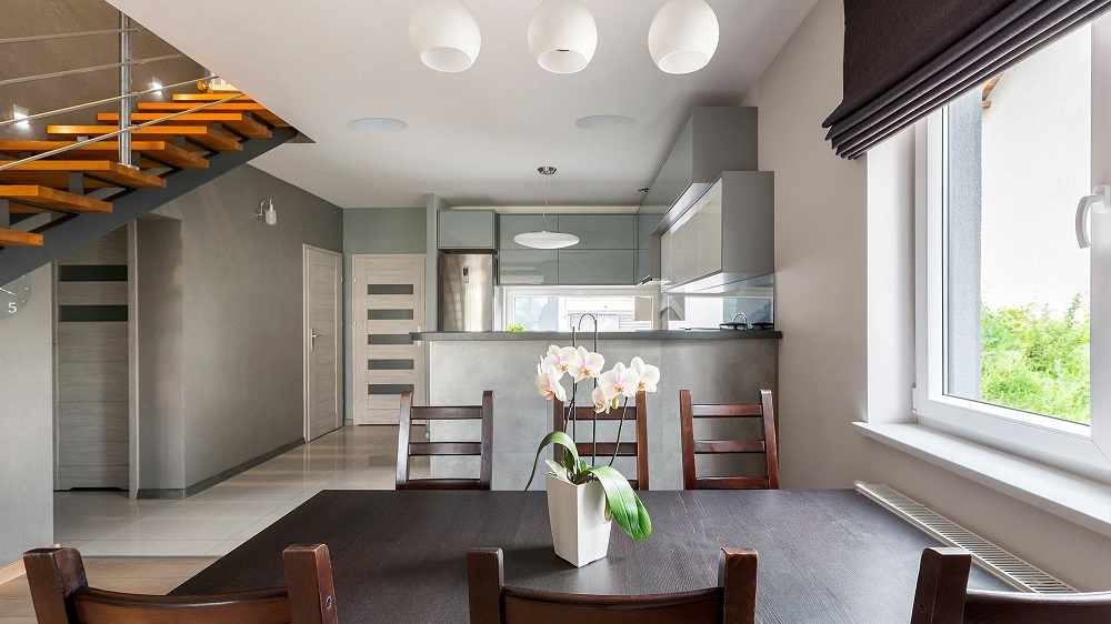 Modernt kök och matplats med takhögtalare och en blombukett.