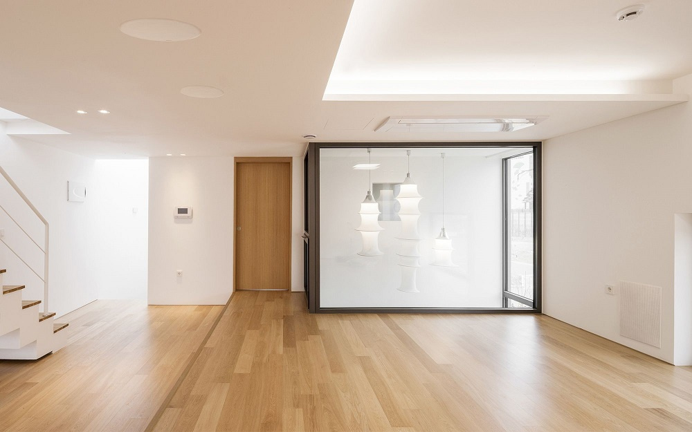 Modernt rum med träddäck och takhögtalare, stora fönster och stilren belysning.