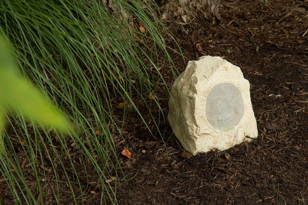 Trädgårdshögtalare som ser ut som en sten, diskret design för utomhusbruk.