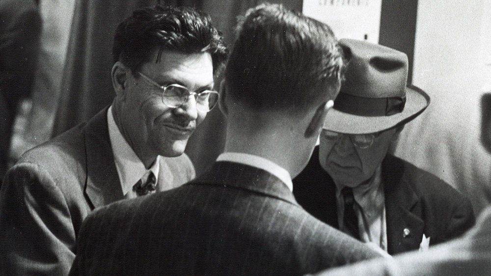 Svartvit bild med tre personer i kostym.