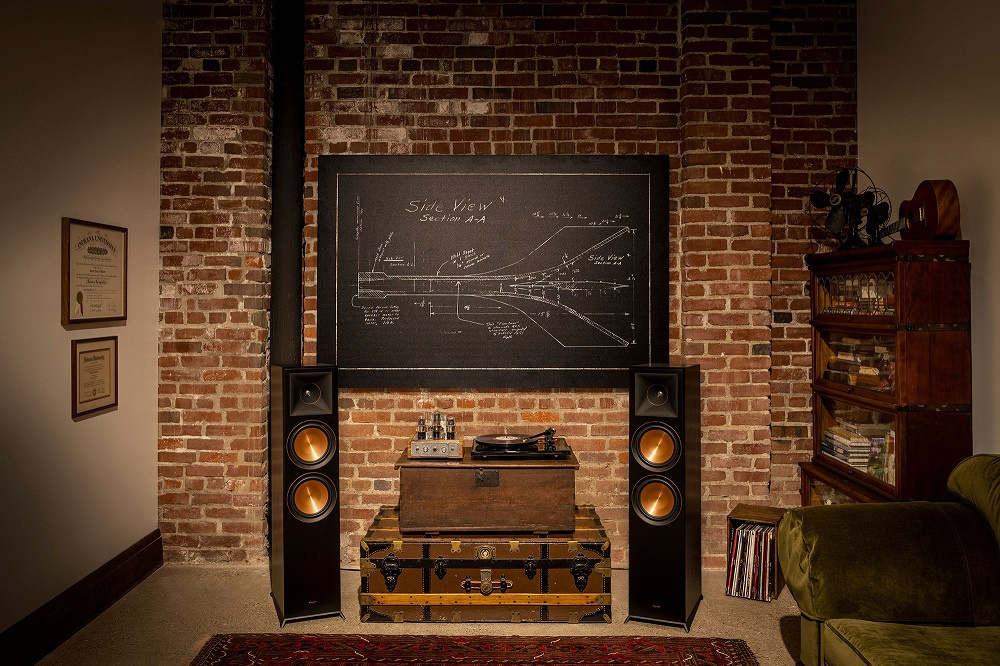 Golvhögtalare i svart med kopparfärgad element, placerade i en stilren miljö.