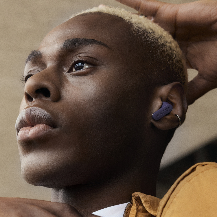 En person med ljust hår och lila hörlurar.