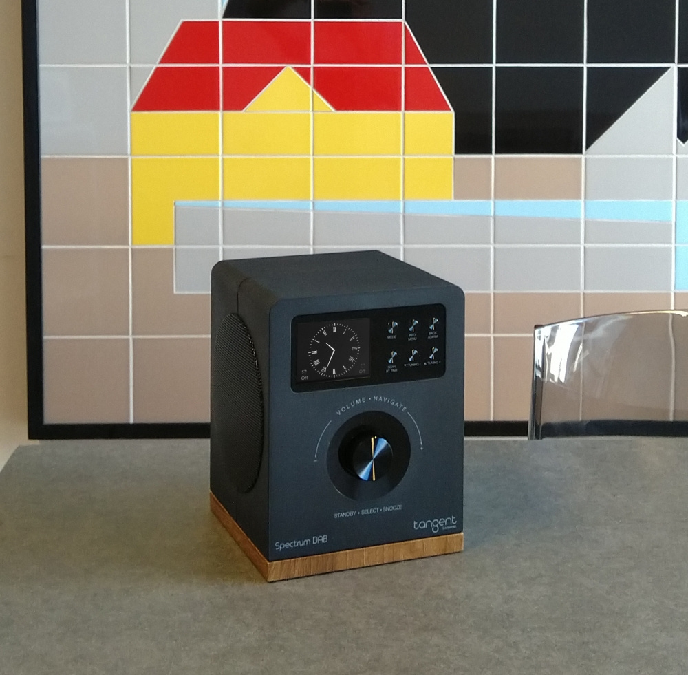 En svart radio med trädetalj och analog klocka.