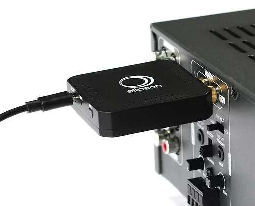 En svart nätverksstreamer ansluten till en ljudanläggning.