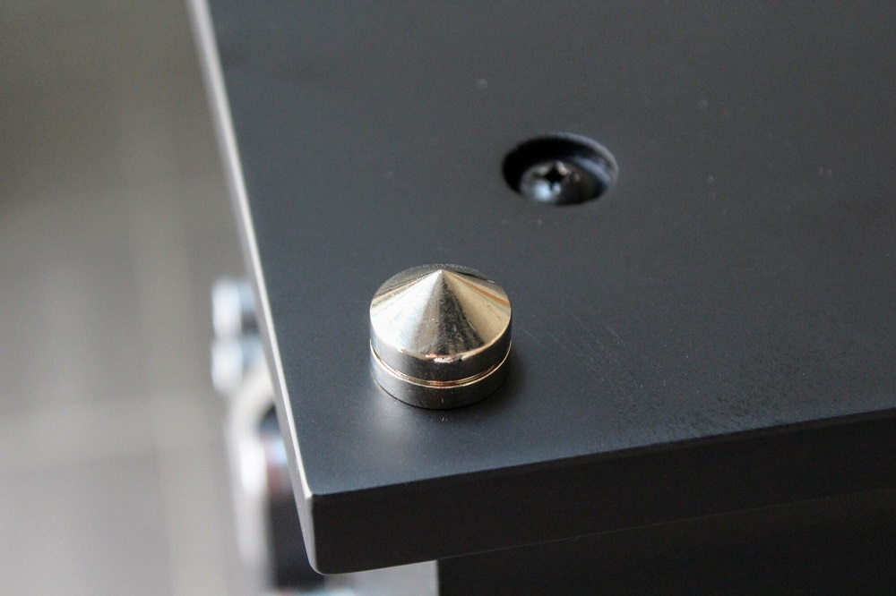 En liten metallknopp på en svart yta, troligtvis del av en högtalare.