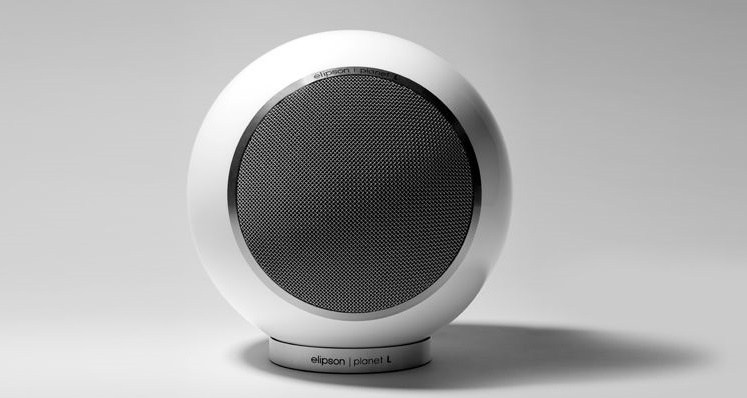 Vitt par runda klothögtalare med silvergrill. Elegant och modern design.