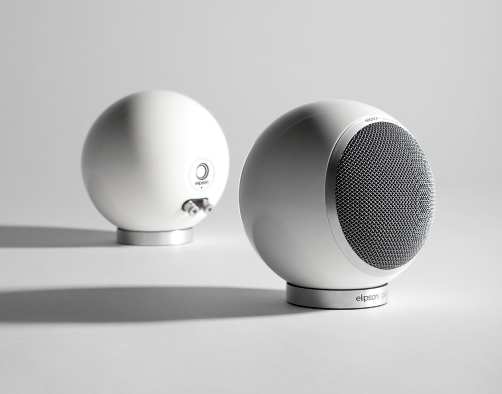 Vita, runda högtalare med grill i metall, minimalistisk design.